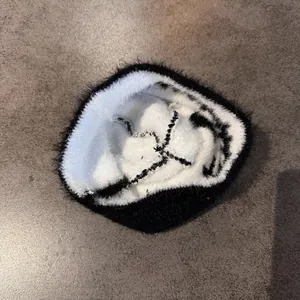 Detail of plush knitted beanie featuring a black and white skull design with X-shaped eyes