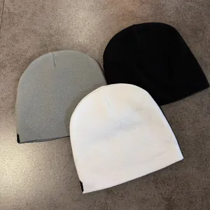 Unisex letter jacquard knit beanie in grey, black and white on stone background