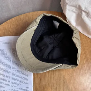 Detail of khaki cotton beret showing black fabric lining and brand label inside