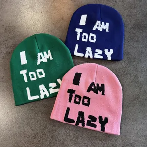 Three colorful knitted beanies with I AM TOO LAZY text on textured stone background
