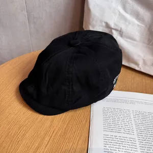 Detail of black cotton newsboy cap featuring white OLD STUDIO NEW YORK side embroidery