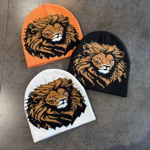 Trois bonnets en tricot noir, blanc et orange avec un motif de tête de lion réaliste
