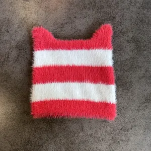 Detalle del gorro de punto con rayas y orejas de gato en suave felpa rosa y blanca