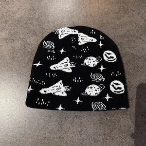 Detailweergave van het ruimte-thema jacquardpatroon met raketten en planeten op de zwarte muts