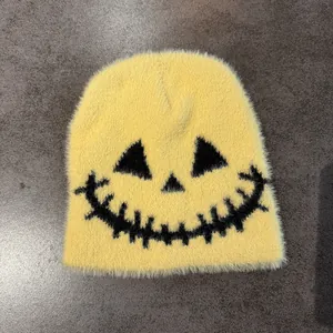 Close-up detail of fluffy yellow knit beanie with a spooky black embroidered smiley face
