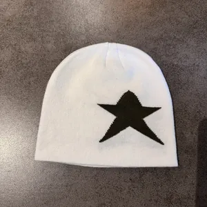 Détail d'un bonnet en tricot blanc avec motif étoile noire sur fond texturé gris