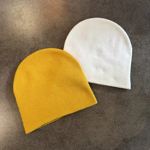 Gros plan de bonnets en maille côtelée jaune et blanc montrant la texture douce