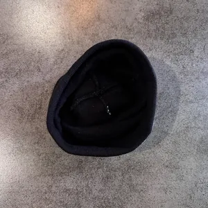 Détail du bonnet en tricot noir montrant la couture en croix et la texture côtelée