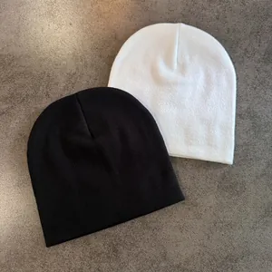 Vue à plat de bonnets en maille noir et blanc avec texture fine sur fond en pierre grise