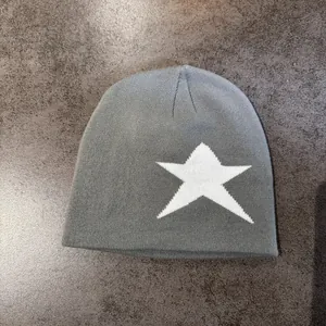 Texture détaillée d'un bonnet gris tricoté avec motif étoile blanche sur tissu épais