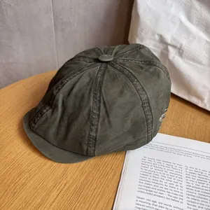 Close-up of vintage dark green cotton beret with white side embroidery on wooden table