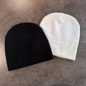 Close-up of black and white knitted beanies showing fine texture and elastic fabric