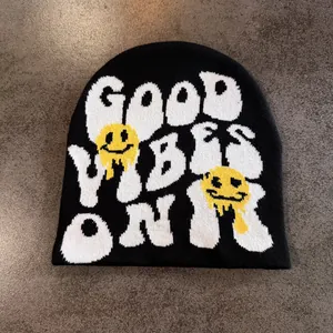 Détail du bonnet en maille avec texte Good Vibes Only et graphismes de smiley fondant