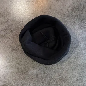 Detailed top view of black ribbed knit beanie showing cross-stitch reinforcement seams