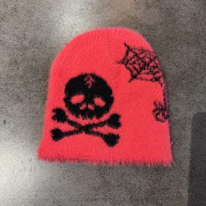 Detail of pink faux mink beanie featuring black skull and spider web knit patterns