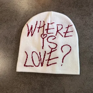 Détail du bonnet blanc en maille avec broderie rouge WHERE IS LOVE? et petit cœur