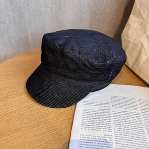 Classic navy blue flat top newsboy hat with textured fabric on a wooden table