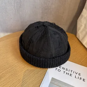 Detail of a black distressed Miki hat featuring torn fabric texture and knitted brim edges