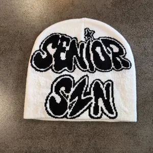 Détail du bonnet en maille blanc avec lettrage graffiti SENIOR SZN noir en jacquard