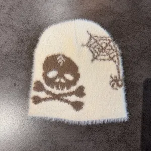 Close-up of the plush knit beanie featuring brown skull and spider web jacquard patterns