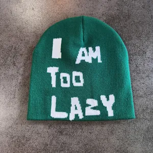 Detailed close-up of green knit beanie with white I AM TOO LAZY text on flat background