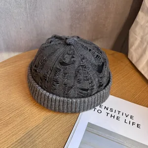 Close-up of distressed gray knit docker cap with vintage rip details and ribbed texture