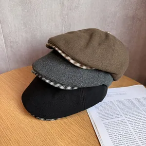 Close-up of three wool newsboy hats in brown, grey, and black with plaid patterns