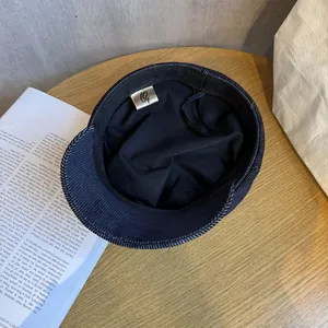 Classic dark navy newsboy cap with gold G-logo label and twill fabric texture