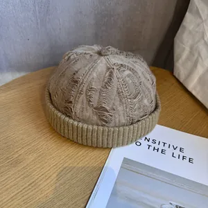 Close-up of retro brown knitted beanie with vintage distressed holes and ribbed texture