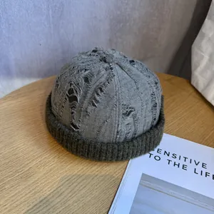 Detail of vintage patchwork brimless cap with heavy distressing and knitted green edge