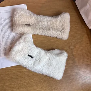 Close-up of plush faux fur headbands in beige and white with subtle rectangle tags
