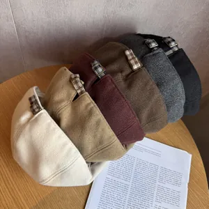Detail of five colored plaid newsboy hats with adjustable straps and metal buckles