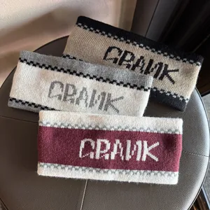 Three Jacquard knitted headbands with CRANK lettering on a grey leather stool