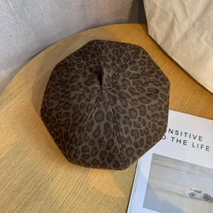Vintage leopard print beret hat for women on a rustic wooden desk with a magazine