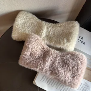 Close-up of soft plush bow headbands in cream and dusty pink faux fur texture