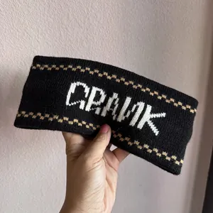 Detail of a black knitted headband featuring white CRANK logo and diamond patterns