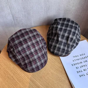 Detail of classic plaid newsboy caps in grey and burgundy on a rustic wooden table