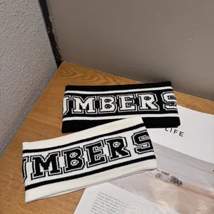 Gros plan de bandeaux de sport tricotés noir et blanc avec lettrage MBERS sur table en bois