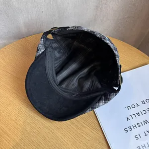 Retro black and white plaid flat cap with black lining on a rustic wooden desk
