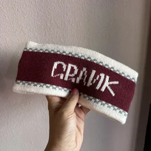Macro shot of knitted wide headband in burgundy with white Crank jacquard lettering