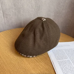 Close-up of brown plaid newsboy cap showing tweed fabric texture and decorative button