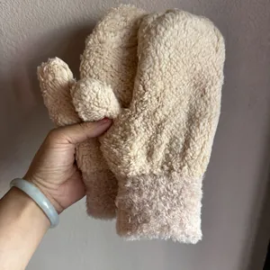 Detail von beigen Sherpa-Plüschfäustlingen mit dicker Textur und elastischen Bündchen