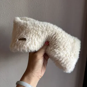 Detail of soft cream faux fur ear warmer headband with rectangular metal tag