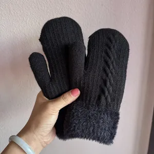 Détail de moufles en tricot torsadé noir avec doublure en fausse fourrure grise