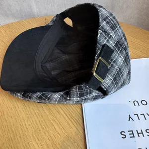 Detail view of the black and white plaid ivy cap with adjustable gold metal buckle