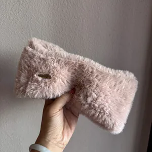 Detail of pink faux fur winter headband featuring a soft fluffy texture and gold metal logo
