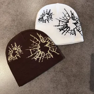 Close-up of white and brown knit beanies with abstract jacquard pattern on textured surface
