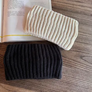 Flat lay of cream and black ribbed knit headbands on wood with magazine detail