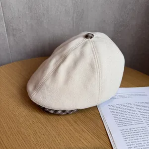 Detail of beige newsboy hat showing brown plaid button and premium textured wool fabric