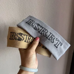 Detail of grey and camel knitted headbands with BSRRT letter jacquard texture